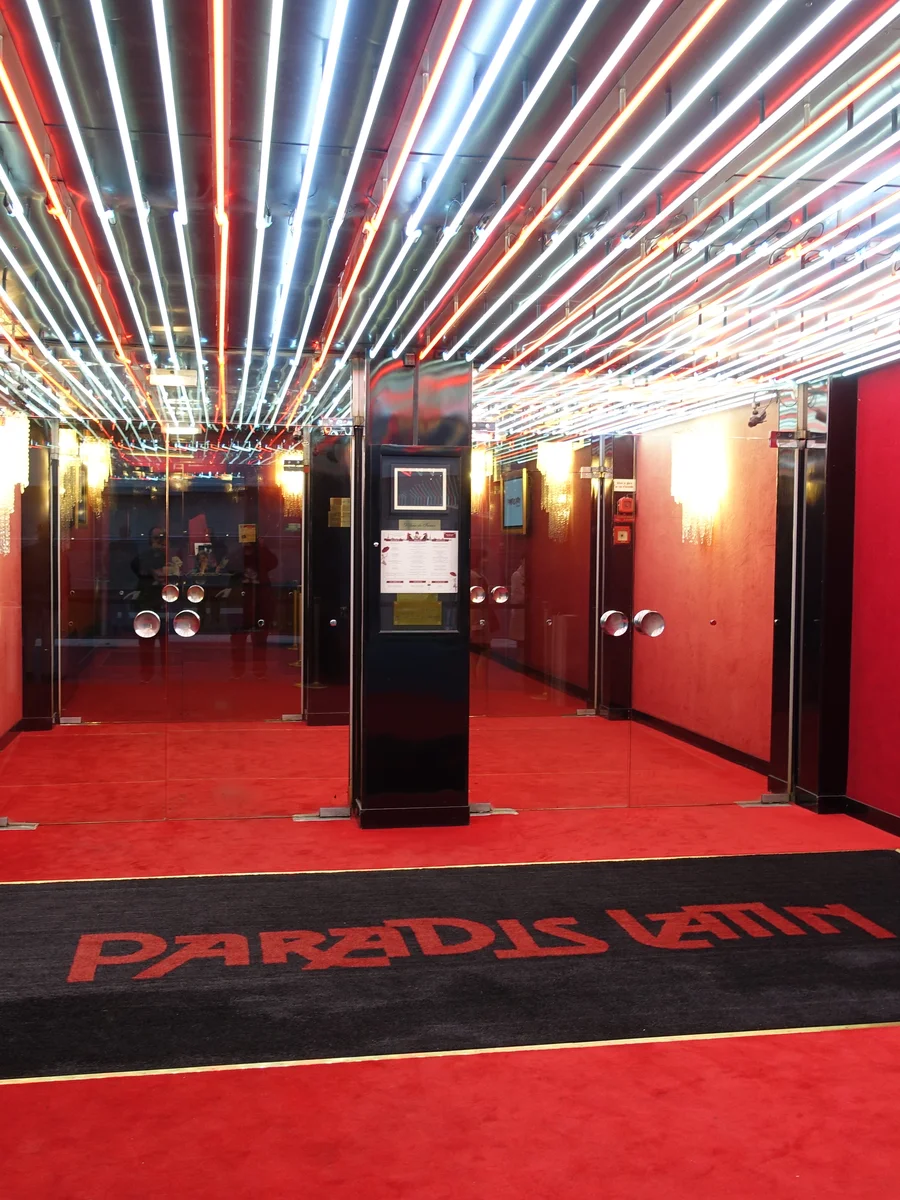 The mirrored, red-carpeted entrance corridor at Paradis Latin, its name set into the carpet