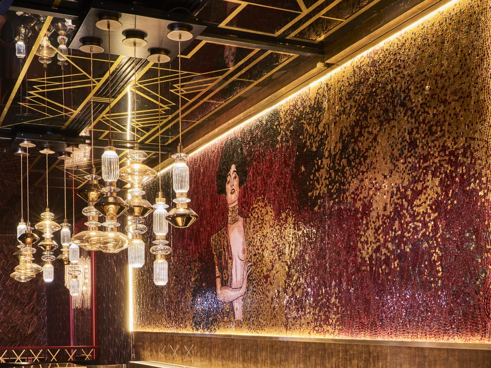 The gold and crimson bar inside Paradis Latin, lit by hanging glass lamps